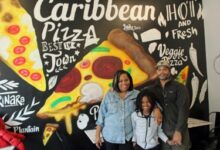 Photo of Eleven-year-old Sebastian Wilson serves ‘Spices & Slices’ at Caribbean style pizza shop in Brooklyn